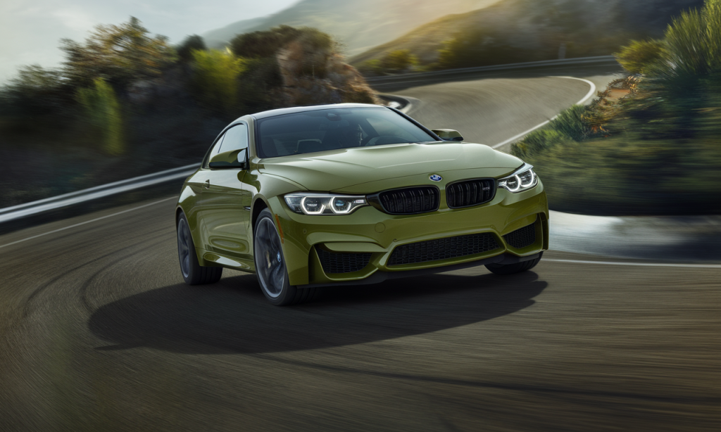 BMW M4 Competition stationnée sur une route avec un paysage en arrière-plan