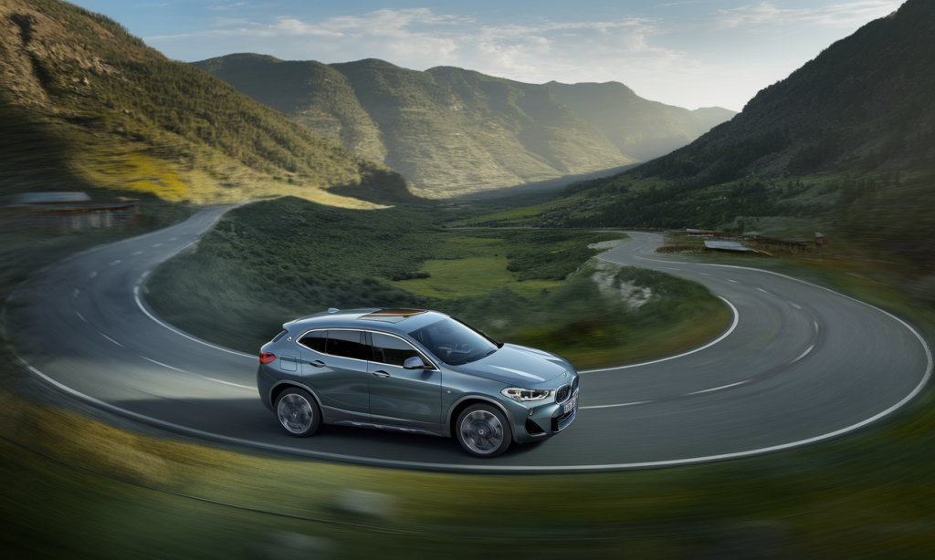 BMW X2 stationnée sur la route avec un coucher de soleil en arrière-plan