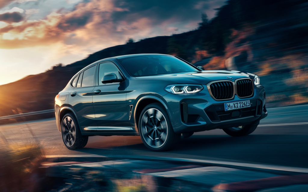 BMW X4 2025 roulant à grande vitesse dans un virage en montagne au coucher du soleil